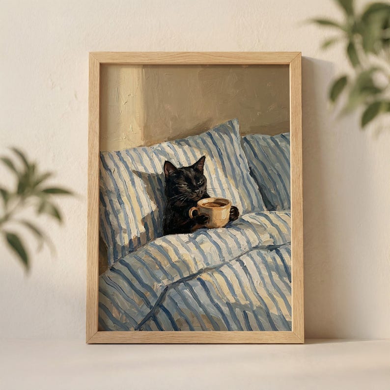 May include: A framed print of a black cat holding a coffee cup while lounging in bed. The bedding has blue and white stripes. The artwork is in a wooden frame.
