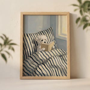 May include: A framed print featuring a white dog reading a book in bed. The bedding and pillow have blue and white stripes. The artwork is in a wooden frame and is set against a light blue wall.