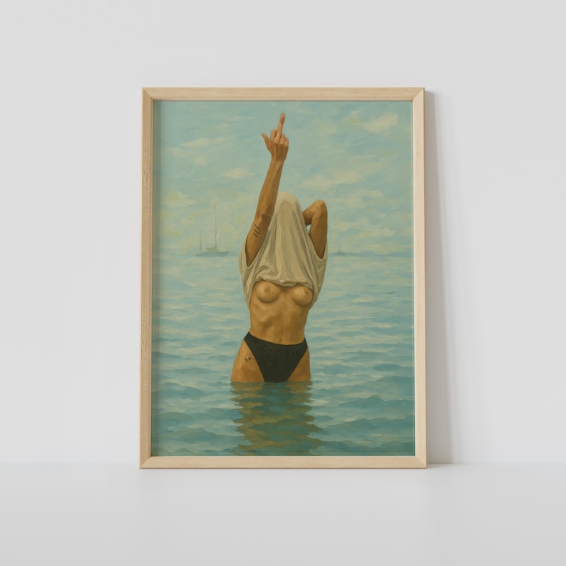 Puede incluir: Una impresi&oacute;n art&iacute;stica enmarcada representa a una persona en el agua, quit&aacute;ndose una camiseta, con el dedo coraz&oacute;n levantado. La persona lleva un traje de ba&ntilde;o negro. El fondo muestra un paisaje marino con veleros y un cielo nublado.