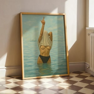 Puede incluir: Impresi&oacute;n art&iacute;stica enmarcada que representa una figura en el agua, parcialmente oculta por una camiseta blanca que se sube por la cabeza. La figura lleva una parte inferior negra, con el dedo coraz&oacute;n levantado. El fondo representa un paisaje marino con veleros.