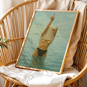 Puede incluir: Una impresi&oacute;n art&iacute;stica enmarcada representa a una persona en el agua, tirando de una camiseta sobre su cabeza. La obra de arte presenta una paleta de colores azul claro y turquesa, con un marco de madera. La persona lleva un traje de ba&ntilde;o negro. El arte se exhibe en una silla de mimbre.