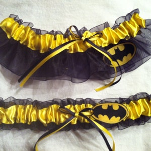 May include: Two black and yellow garters with a black Batman logo on each. The garters are made of black tulle and yellow satin.