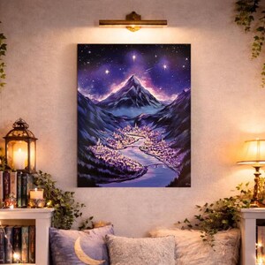 May include: A large, vertical painting depicts a nighttime landscape with a mountain range under a starry sky. A river flows through a valley with a city illuminated in purple and white lights. The artwork is mounted on a wall above a cozy seating area.