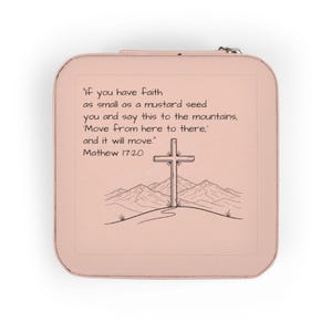 May include: A blush pink jewelry case with a zipper closure. The case features a printed design of a cross on a hill with mountains in the background and the text "If you have faith as small as a mustard seed..." from Matthew 17:20.
