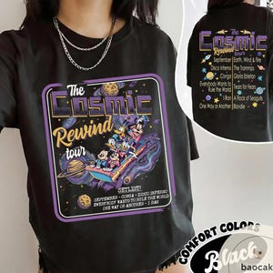 May include: Black t-shirt featuring a graphic for "The Cosmic Rewind Tour." The design includes cartoon characters on a space-themed ride, with text listing the setlist and tour details. The back of the shirt also has the tour name and setlist.