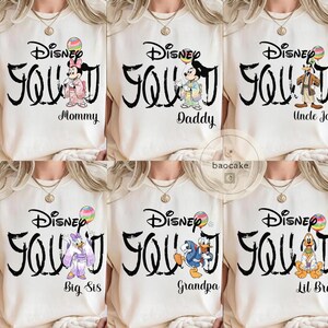 Puede incluir: Camisetas familiares de Disney color crema con texto negro "Disney Squad". Cada camiseta presenta un personaje diferente de Disney y un rol familiar: Mam&aacute;, Pap&aacute;, T&iacute;o Jo, Hermana Mayor, Abuelo y Hermano Peque&ntilde;o.