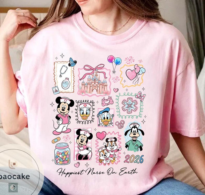 May include: Pink t-shirt with a colorful graphic featuring Disney characters in nurse attire. The design includes Mickey and Minnie Mouse, Donald Duck, and Goofy, along with medical symbols and the text "Happiest Nurse On Earth" and the year 2026.