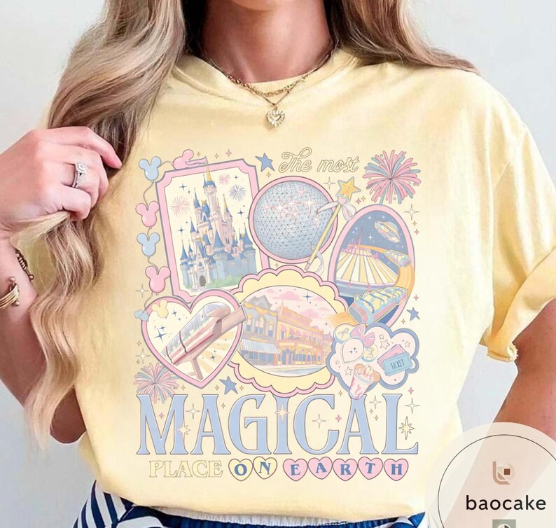May include: A pale yellow t-shirt with a colourful graphic design. The design features the text "The most MAGICAL PLACE ON EARTH" and illustrations of a castle, a sphere, and other theme park elements in pastel colours.