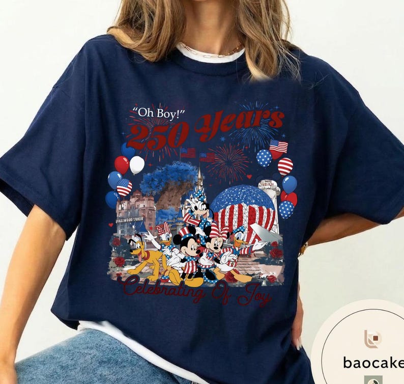 Puede incluir: Camiseta azul marino con un dise&ntilde;o de personajes de Disney, fuegos artificiales y globos. La camiseta muestra el texto "Oh Boy! 250 Years Celebrating of Joy". El dise&ntilde;o incorpora banderas americanas y colores patri&oacute;ticos.