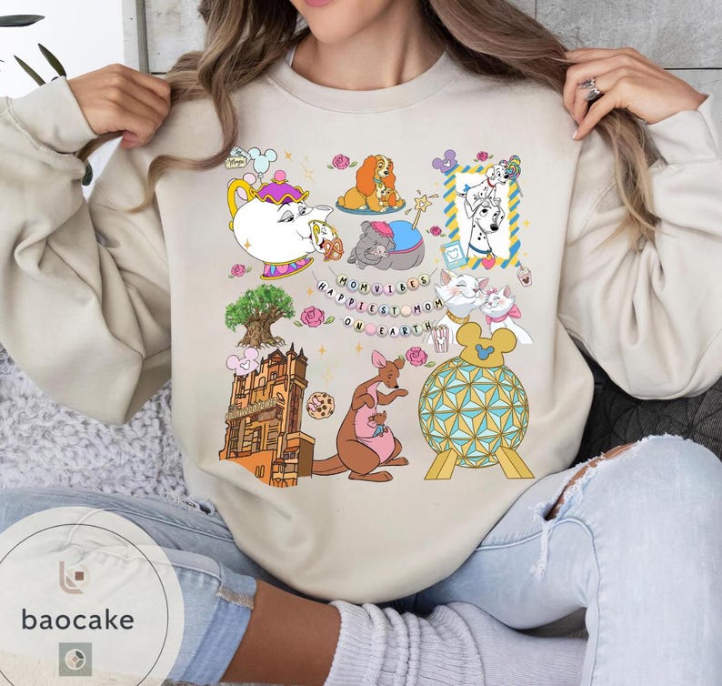 May include: Beige sweatshirt with colorful cartoon illustrations of Disney characters and landmarks. The design includes a teapot, dogs, cats, a kangaroo, and the text "Mom Vibes Happiest Mom on Earth."