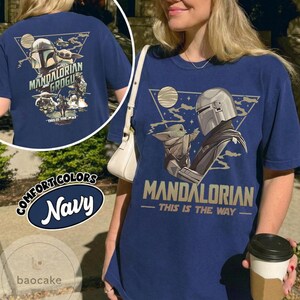 Op de afbeelding: Marineblauw T-shirt met een afbeelding van The Mandalorian en Grogu. Het ontwerp bevat de tekst "MANDALORIAN" en "THIS IS THE WAY". Het shirt maakt deel uit van de Comfort Colors collectie.