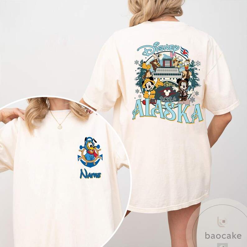May include: Cream-colored t-shirt featuring Disney characters and the text "Alaska 2024." The back of the shirt displays a colorful graphic with Mickey and Minnie Mouse, Donald Duck, and Goofy. The front has a smaller graphic of Donald Duck on a blue anchor with the word "Name."