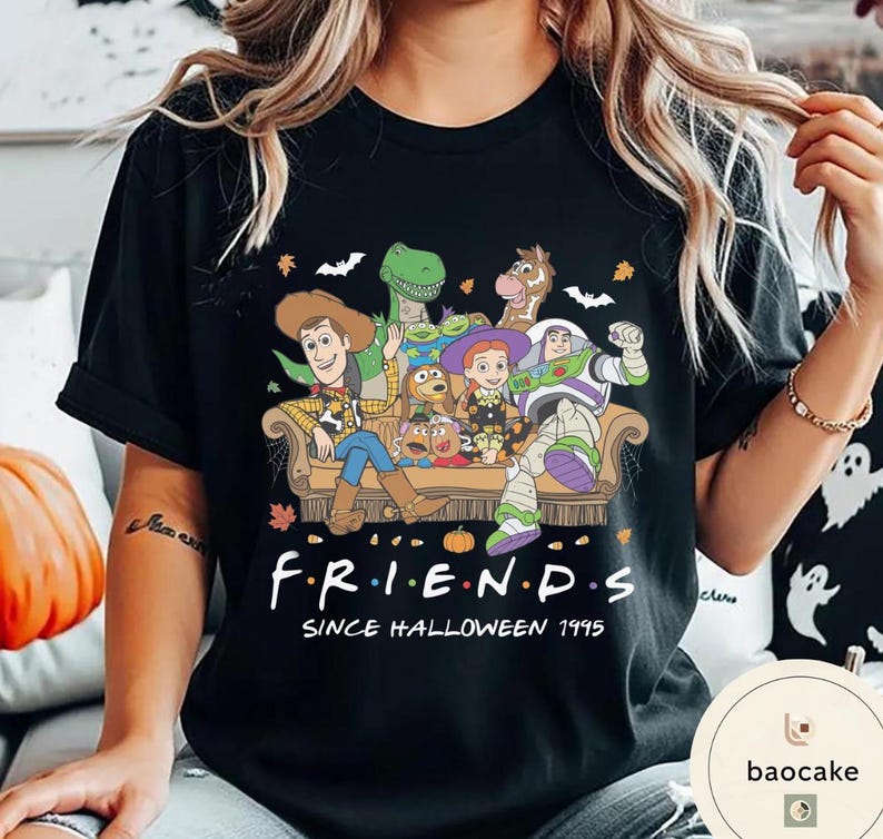 May include: A black t-shirt featuring a graphic print of Toy Story characters sitting on a couch with Halloween elements like bats and leaves. The text reads F R I E N D S SINCE HALLOWEEN 1995. The design includes Woody, Buzz Lightyear, Jessie, Rex, Bullseye, and Mr. Potato Head.