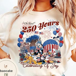 Puede incluir: Camiseta color crema con un dise&ntilde;o patri&oacute;tico con Mickey Mouse, Minnie Mouse, Donald Duck y Goofy. El gr&aacute;fico incluye fuegos artificiales, globos y el texto "Oh Boy! 250 Years Celebrating Of Joy."