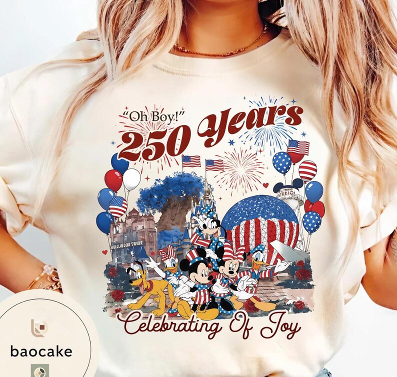 Puede incluir: Camiseta color crema con un dise&ntilde;o patri&oacute;tico con Mickey Mouse, Minnie Mouse, Donald Duck y Goofy. El gr&aacute;fico incluye fuegos artificiales, globos y el texto "Oh Boy! 250 Years Celebrating Of Joy."