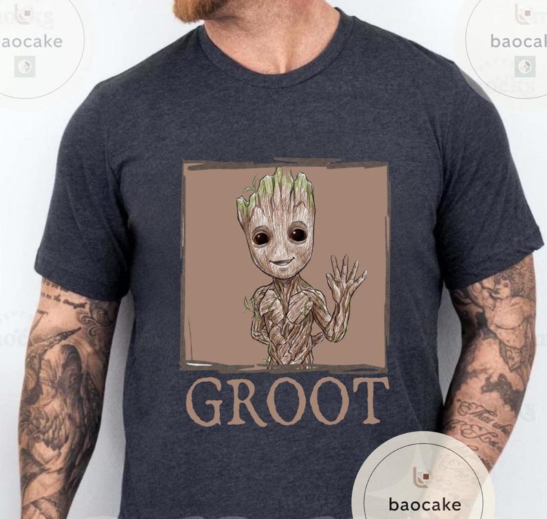 May include: Dark gray t-shirt featuring a Groot graphic. The illustration shows Groot waving with a friendly expression, set within a brown square. The word "GROOT" is printed in brown below the image.