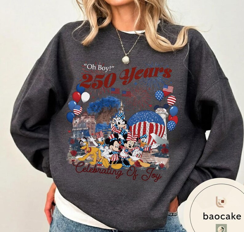 Puede incluir: Sudadera gris oscuro con un gr&aacute;fico colorido que celebra 250 a&ntilde;os. El dise&ntilde;o incluye fuegos artificiales, globos y personajes de Disney. El texto incluye "Oh Boy!" y "Celebrating of Joy."