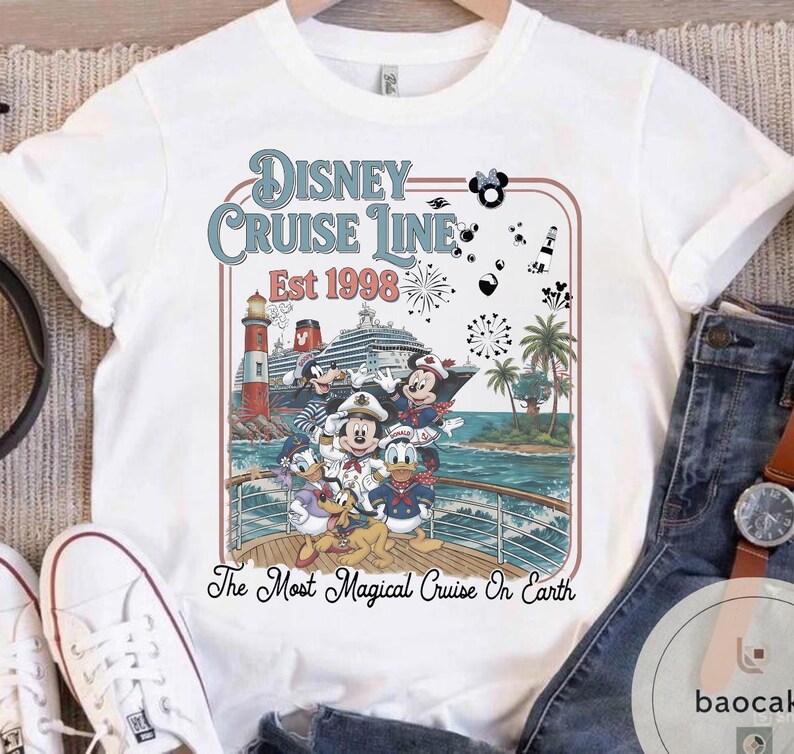 Puede incluir: Camiseta blanca con un gr&aacute;fico colorido de personajes de Disney en un crucero. El dise&ntilde;o incluye el texto "Disney Cruise Line Est 1998" y "The Most Magical Cruise On Earth". La camiseta tiene cuello redondo y mangas cortas.
