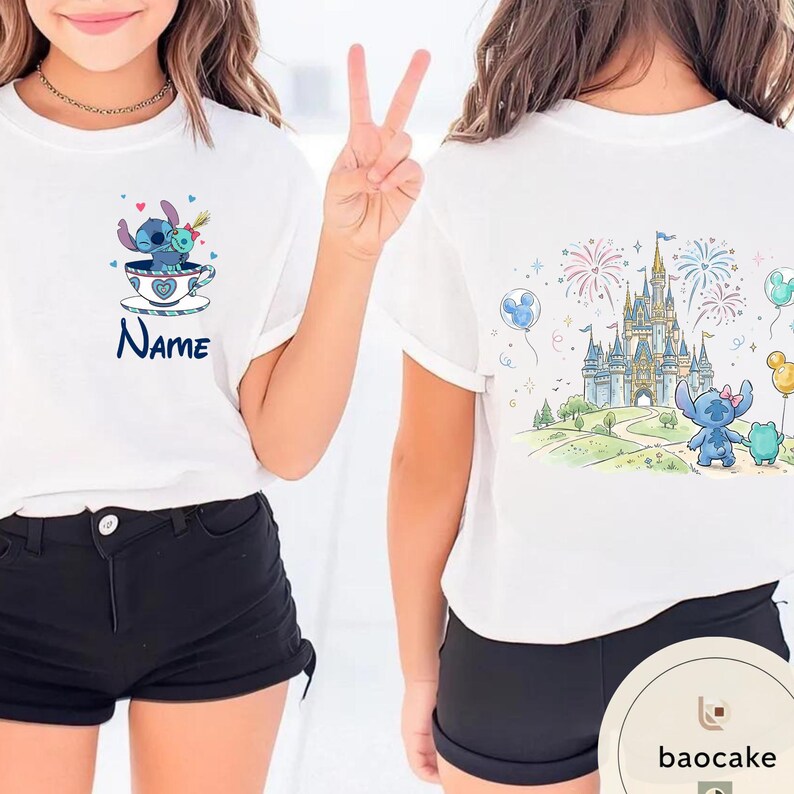 May include: White t-shirts with cartoon graphics. One shirt features a blue character in a teacup with the name "Name". The other shirt displays a castle, fireworks, and a blue character with a green friend.