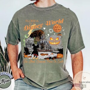 May include: Moss green t-shirt featuring a Halloween-themed Disney World graphic. The design includes a castle, Mickey Mouse, pumpkins, and the text "Florida Disney World" and "The Most Scariest Place On Earth."