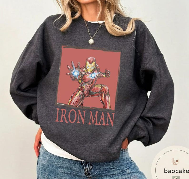 May include: Dark gray sweatshirt featuring a red and gold Iron Man graphic on a red background. The words "IRON MAN" are printed in red below the graphic. The sweatshirt is a crew neck style.