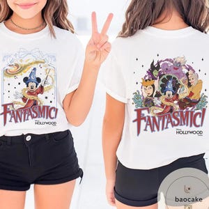 May include: White t-shirt featuring a graphic of Mickey Mouse in a sorcerer's hat with the text "Fantasmic! Hollywood" on the front. The back of the shirt displays Disney villains and Mickey Mouse. The shirt is paired with black shorts.