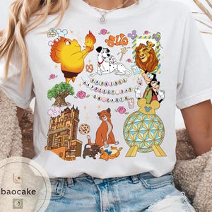 May include: White t-shirt featuring colorful cartoon characters and the text "Happiest Dad on Earth." The design includes images of a lion, Dalmatian dogs, Mickey Mouse, and other animated figures. The shirt has a crew neck and short sleeves.