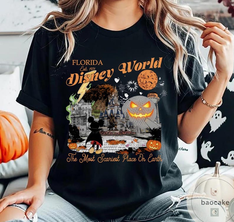 May include: Black t-shirt featuring a Halloween-themed graphic with the text "Florida Disney World Est. 1971." The design includes a jack-o'-lantern, Mickey Mouse, and a castle. The phrase "The Most Scariest Place On Earth" is also printed on the shirt.
