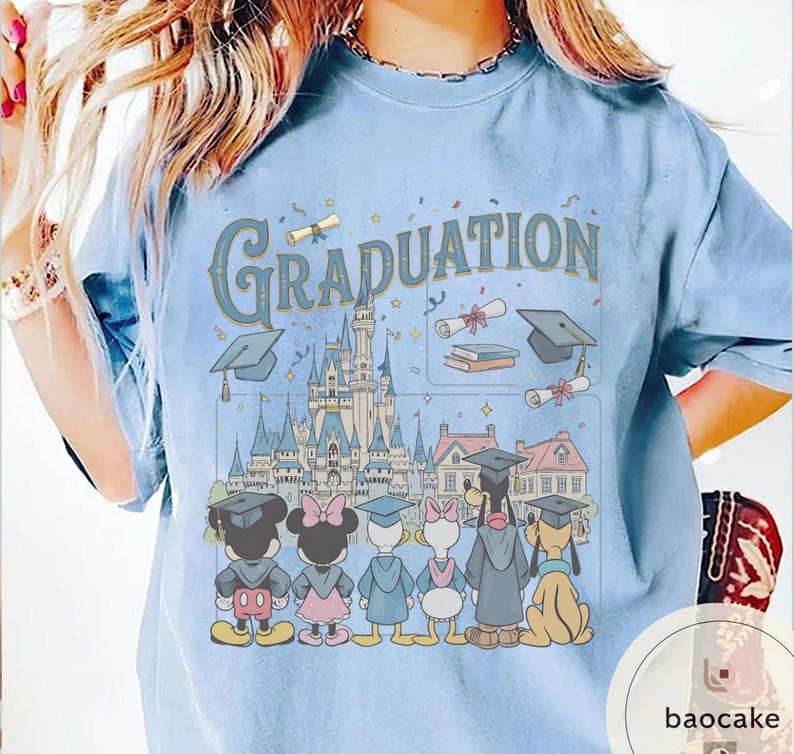 May include: Light blue t-shirt with the word "Graduation" in a vintage font. The graphic features Disney characters in graduation attire, standing in front of a castle and other buildings. The design includes graduation caps, diplomas, and books.