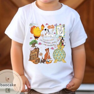 May include: White t-shirt featuring a colorful graphic with cartoon characters and the text "Happiest Day on Earth." The design includes a variety of animated figures, a tree, and a building. The shirt is worn by a child.