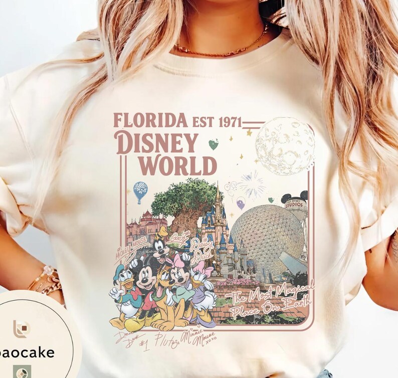 May include: A cream-colored crewneck sweatshirt featuring a graphic print with the text FLORIDA EST 1971 DISNEY WORLD and The Most Magical Place On Earth. The design includes illustrations of Disney characters, a castle, and a geodesic dome.