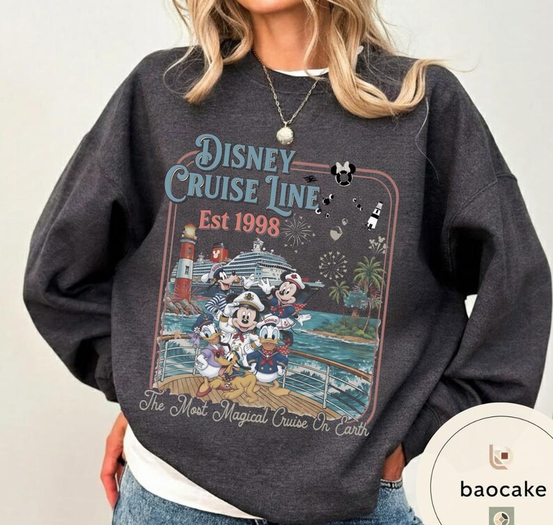 Puede incluir: Sudadera gris oscuro con un dise&ntilde;o de Disney Cruise Line. El gr&aacute;fico incluye a Mickey Mouse, el Pato Donald y otros personajes en un crucero, con el texto "Disney Cruise Line Est 1998" y "The Most Magical Cruise On Earth."