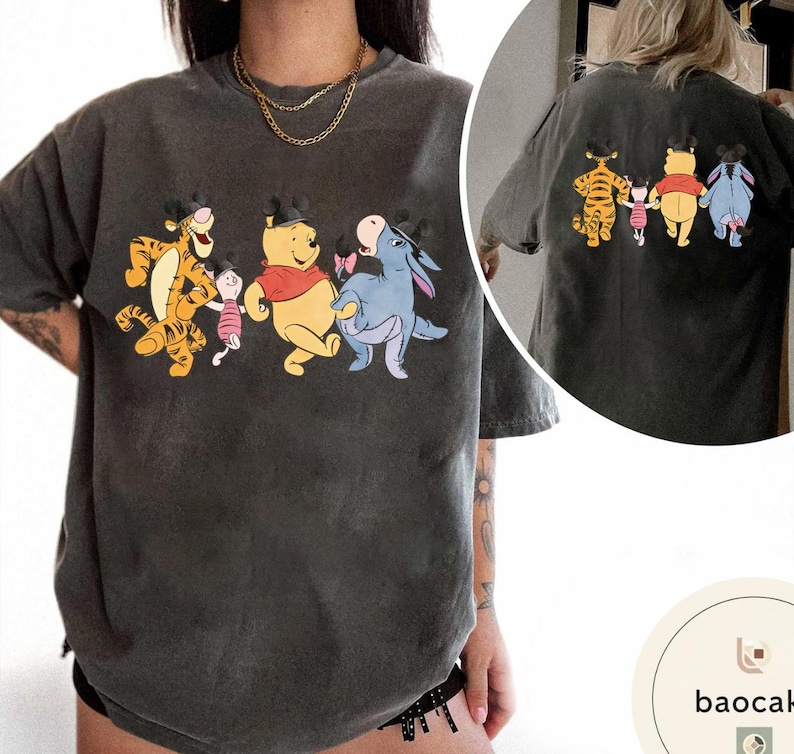 May include: Dark gray t-shirt featuring a colorful graphic of Winnie the Pooh and friends. The front of the shirt shows Tigger, Piglet, Winnie the Pooh, and Eeyore. The back of the shirt shows the same characters. The shirt has a vintage wash.