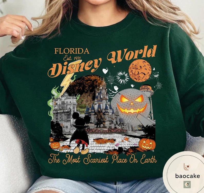 May include: Dark green sweatshirt with a Halloween-themed graphic. The design includes text that reads "FLORIDA Disney World Est. 1971" and "The Most Scariest Place On Earth". The graphic features a Mickey Mouse character, a pumpkin, and a castle.
