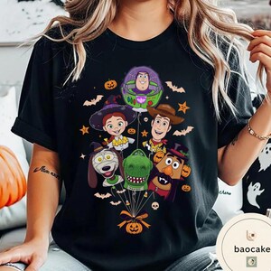 Pode incluir: Uma t-shirt preta com uma impress&atilde;o gr&aacute;fica de personagens de Toy Story vestidos para o Halloween. O design mostra Buzz Lightyear, Woody, Jessie, Rex, Slinky Dog e Mr. Potato Head como bal&otilde;es presos a uma ab&oacute;bora, rodeados por morcegos.