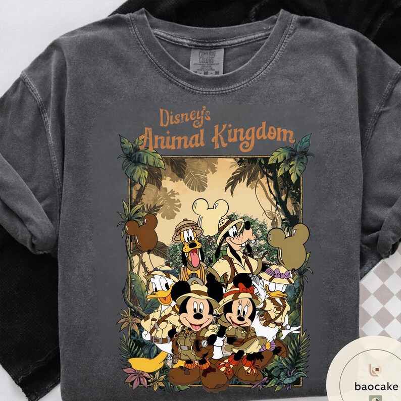 May include: Dark gray t-shirt featuring a graphic of Disney's Animal Kingdom characters, including Mickey and Minnie Mouse, Donald Duck, Goofy, and Pluto, in safari attire. The text "Disney's Animal Kingdom" is displayed above the characters.