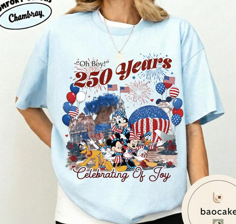 Puede incluir: Camiseta azul claro con un dise&ntilde;o que celebra 250 a&ntilde;os. El dise&ntilde;o incluye a Mickey, Minnie, Donald y Pluto con atuendos patri&oacute;ticos, junto con fuegos artificiales, globos y banderas americanas. El texto incluye "Oh Boy!" y "Celebrating Of Joy."