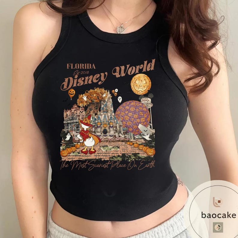Op de afbeelding: Zwarte tanktop met een Halloween-thema Disney World-afbeelding. Het ontwerp bevat Donald Duck in kostuum, pompoenen en de tekst "The Most Scariest Place On Earth."