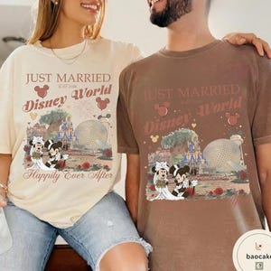 May include: Two t-shirts, one cream and one brown, featuring a Disney World design. The design includes the text "Just Married" and "Happily Ever After", along with images of Mickey and Minnie Mouse in wedding attire, and Disney landmarks.