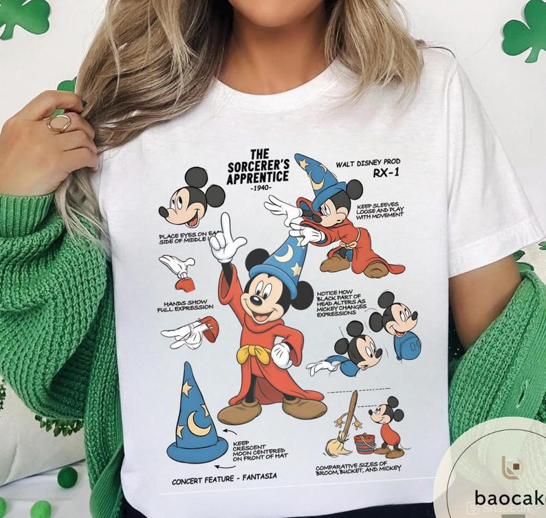May include: White t-shirt featuring a graphic of Mickey Mouse as the Sorcerer's Apprentice. The design includes illustrations and text detailing the character's features and the film's production details. The shirt has a crew neck and short sleeves.
