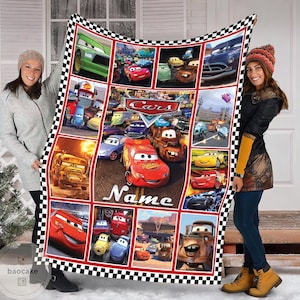 May include: A rectangular fleece blanket featuring a collage of scenes from the Disney Pixar movie Cars, including Lightning McQueen and Mater. The blanket has a black and white checkered border and the word Name printed in white script.