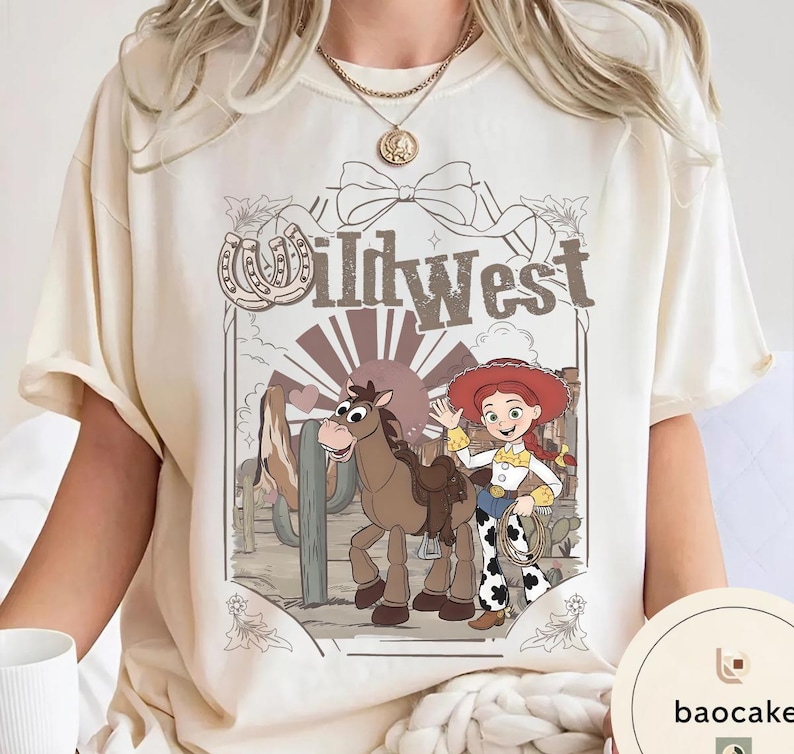 Pu&ograve; includere: T-shirt color crema con un design del West selvaggio. La grafica include un cartone animato di una cowgirl con un lazo, un cavallo e la scritta "Wildwest". Il design ha uno stile vintage, a cartoni animati, con uno sfondo di paesaggio desertico.