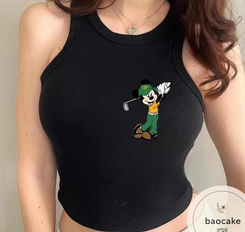 May include: Black tank top featuring a colorful cartoon of Mickey Mouse playing golf. Mickey is wearing a green hat, green pants, and a yellow shirt. The tank top is sleeveless and has a round neckline.