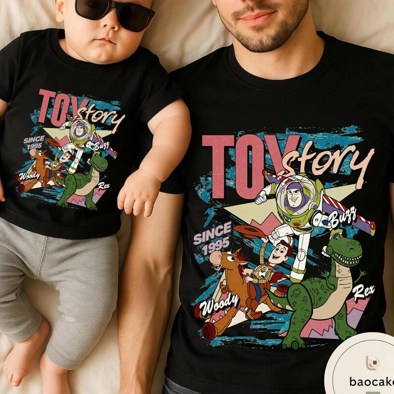 May include: Black t-shirts featuring the Toy Story logo and characters, including Buzz Lightyear, Woody, and Rex. The shirts have the text "TOY STORY" and "SINCE 1995". The design is in shades of pink, blue, green, and brown.