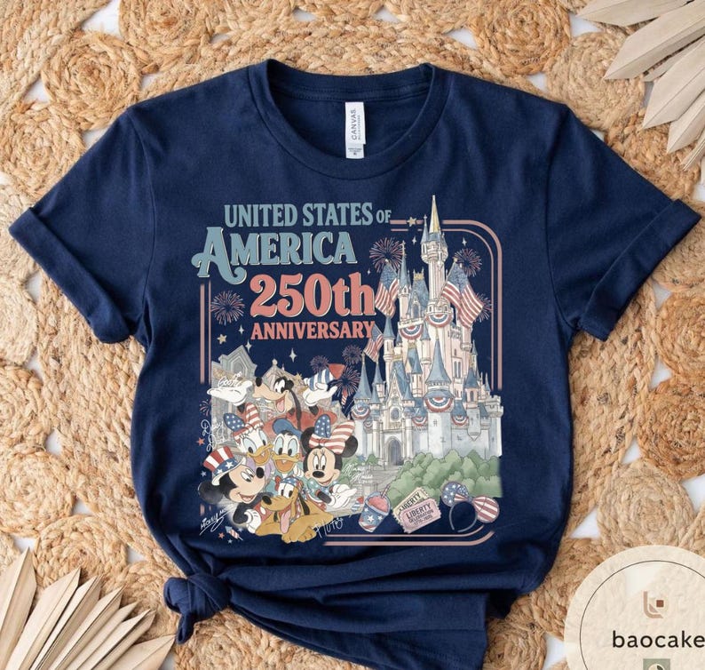 May include: Navy blue t-shirt with a graphic celebrating the 250th anniversary of the United States of America. The design includes a castle, fireworks, and cartoon characters like Mickey and Minnie Mouse.