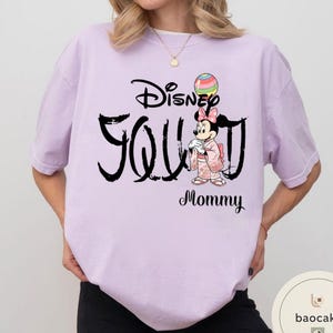 Puede incluir: Camiseta lila claro con el texto negro "Disney You Mommy". La camiseta presenta un gr&aacute;fico de Minnie Mouse con un kimono sosteniendo un globo colorido. La camiseta es de corte holgado.