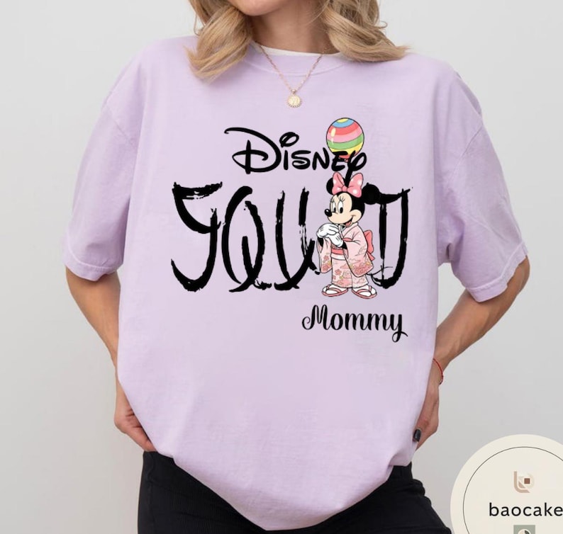 Puede incluir: Camiseta lila claro con el texto negro "Disney You Mommy". La camiseta presenta un gr&aacute;fico de Minnie Mouse con un kimono sosteniendo un globo colorido. La camiseta es de corte holgado.