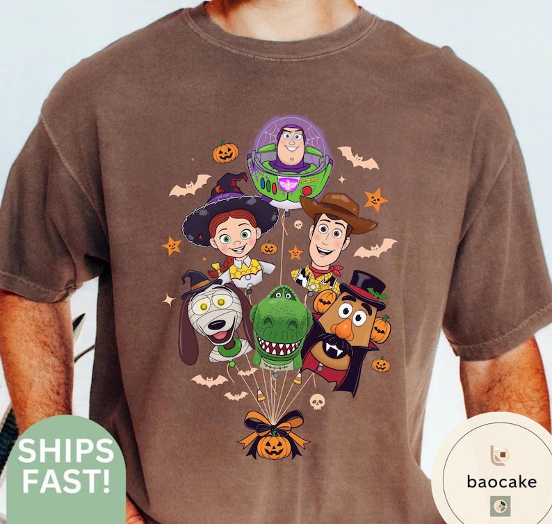 Pode incluir: Uma t-shirt castanha de manga curta com uma impress&atilde;o gr&aacute;fica de personagens de Toy Story vestidos para o Halloween. O design mostra Buzz Lightyear, Woody, Jessie, Slinky Dog, Rex e Mr. Potato Head como bal&otilde;es presos a uma ab&oacute;bora com um la&ccedil;o preto.