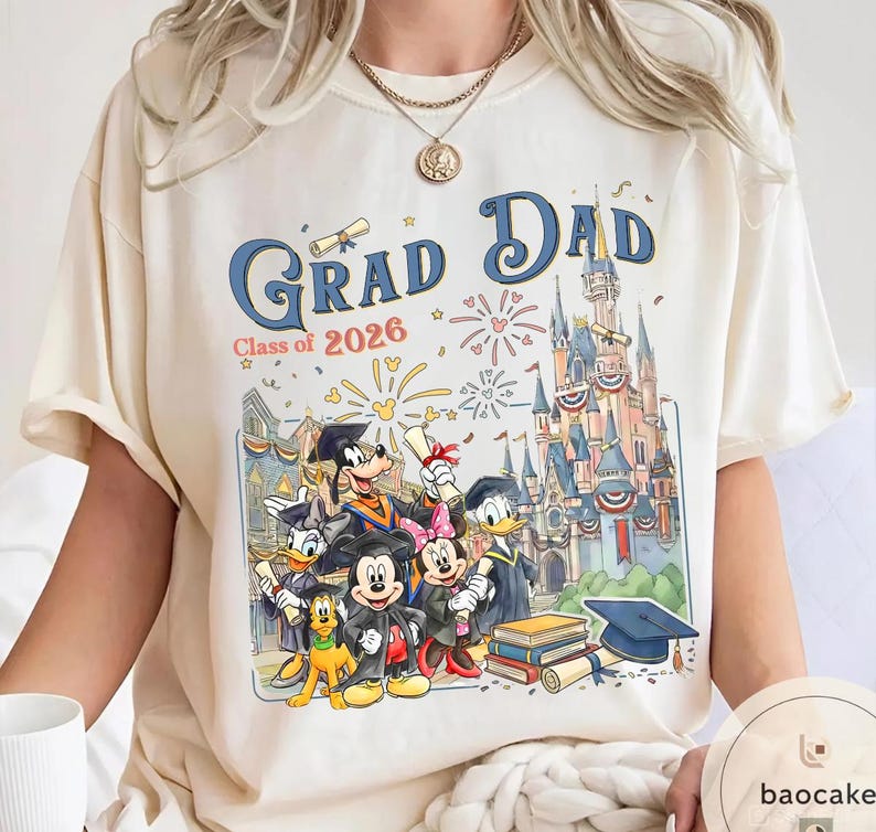 May include: Cream-coloured t-shirt with a colourful graphic featuring Disney characters and the text "Grad Dad Class of 2026." The design includes Mickey Mouse, Minnie Mouse, Donald Duck, Goofy, and Pluto, with a castle backdrop.