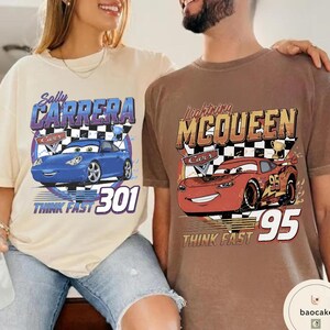 Puede incluir: Dos camisetas con personajes de la pel&iacute;cula Cars. Una es beige con un coche azul y el texto "Sally Carrera 301 THINK FAST". La otra es marr&oacute;n con un coche rojo y el texto "Lightning McQueen 95 THINK FAST".